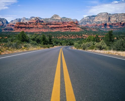 Road in Arizona with red rocks in the background.