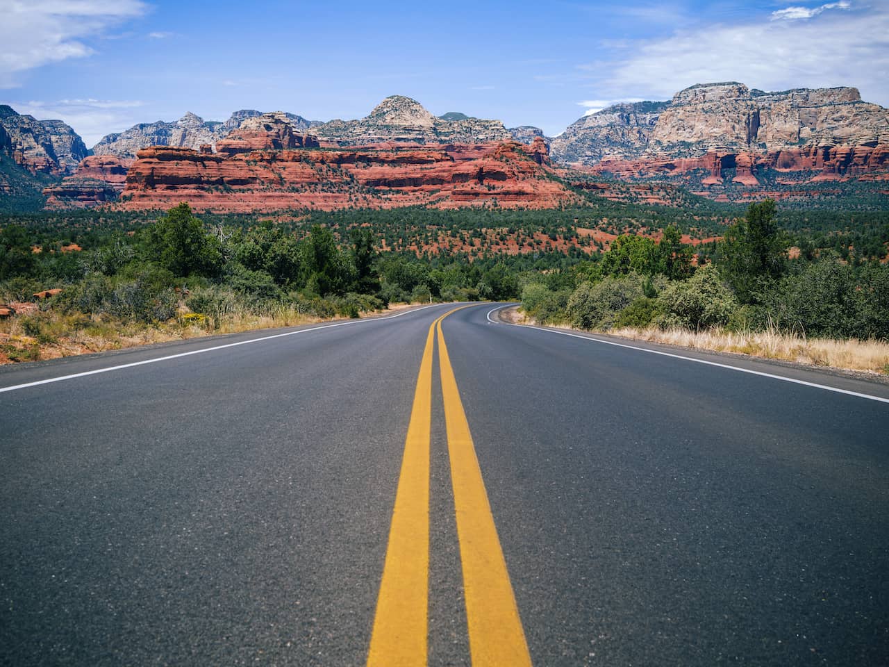 Road in Arizona with red rocks in the background.