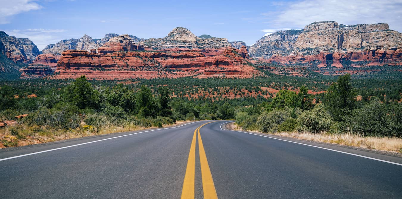 Road in Arizona with red rocks in the background.