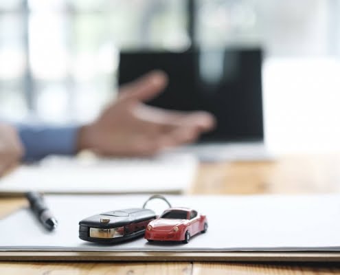 Car keys and small toy car on notepad.