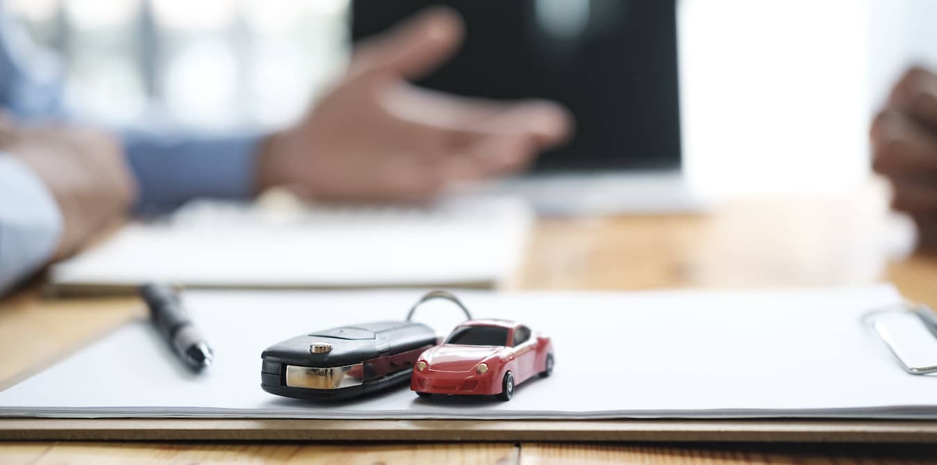 Car keys and small toy car on notepad.